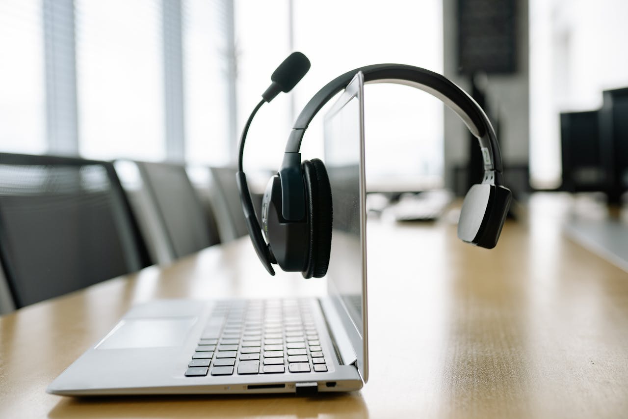 about-us Sleek laptop with a wireless headset in a bright, modern office setting.